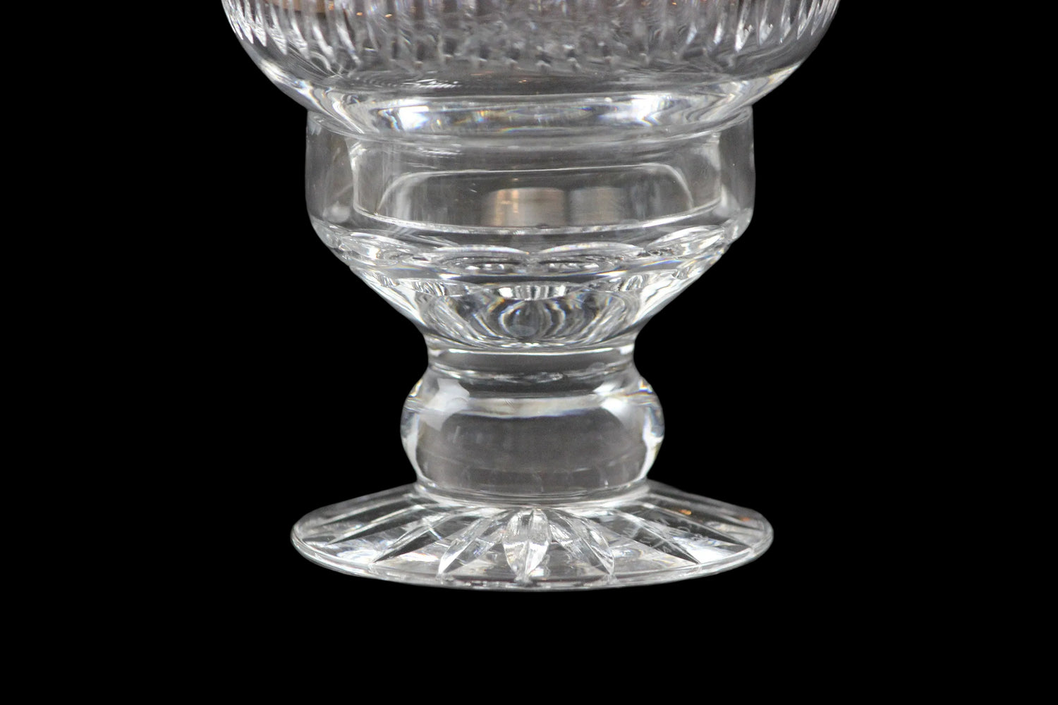 Clear glass hurricane lamp with intricate cut patterns on a black 