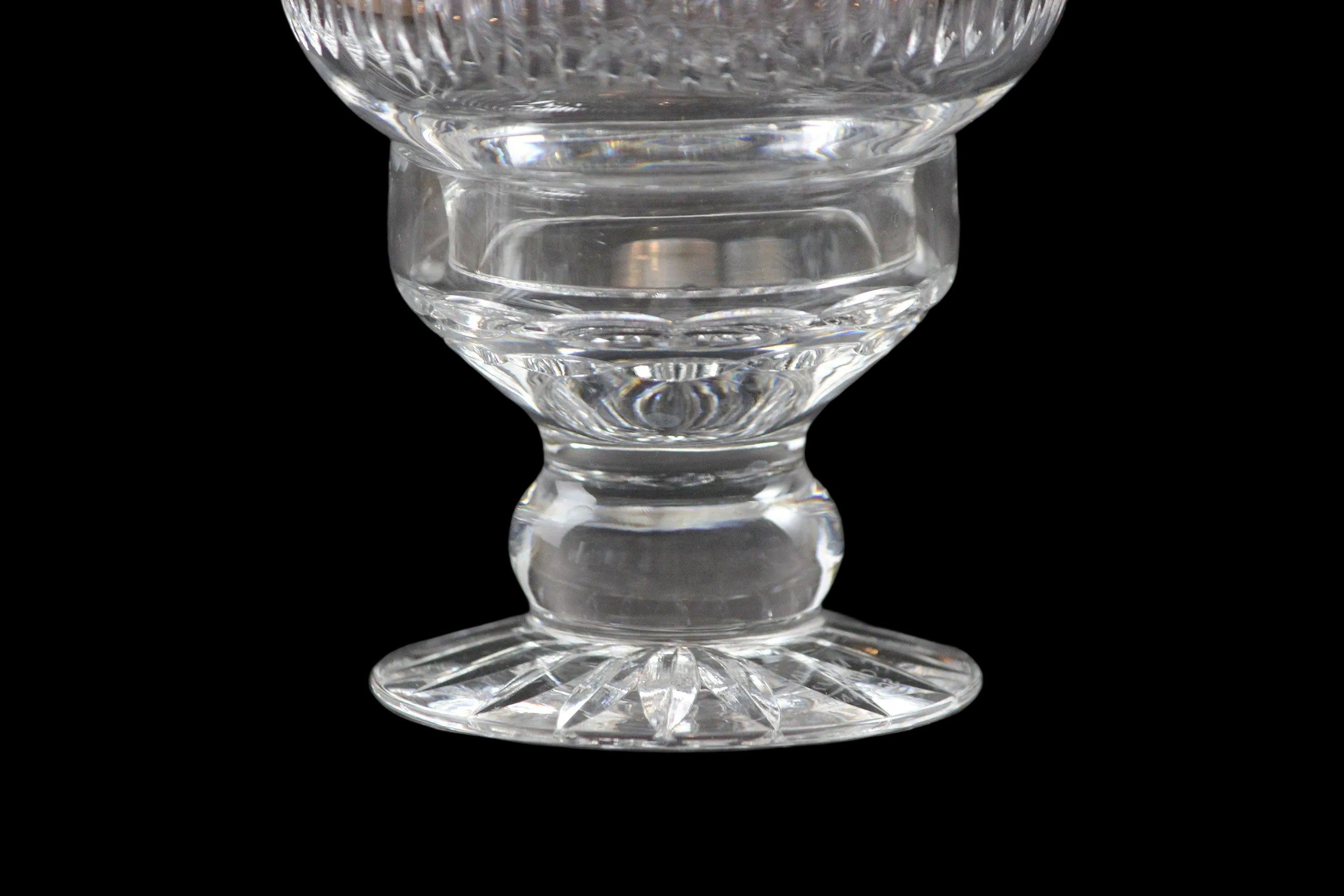 Clear glass hurricane lamp with intricate cut patterns on a black 