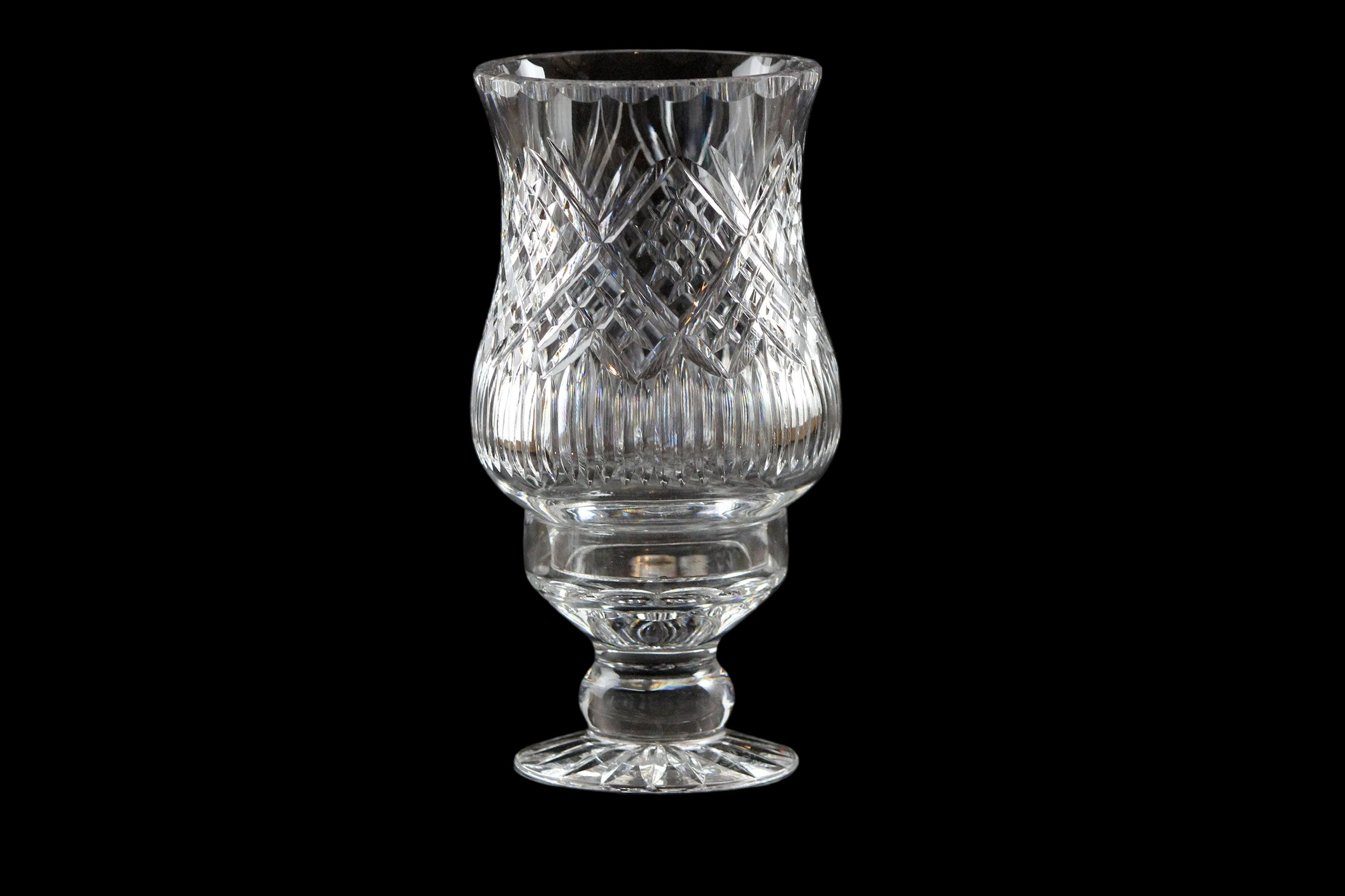 Clear glass hurricane lamp with intricate design on a black background