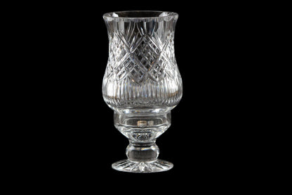Clear glass hurricane lamp with intricate design on a black background