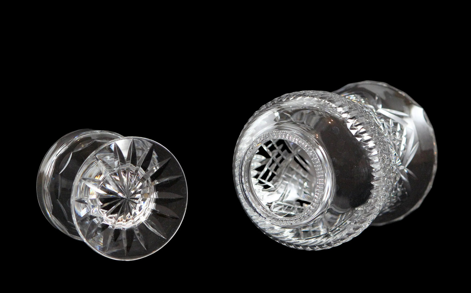 Clear glass hurricane lamp with intricate cut patterns on a black 