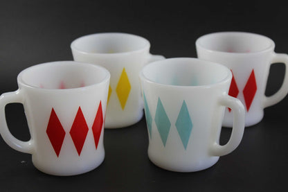 Set of four (4) white glass coffee mugs with a red, yellow, teal and red harlequin diamond pattern, set against a dark gray background.