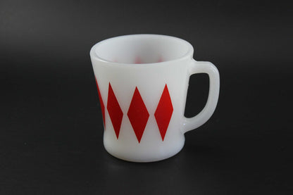 A second white glass coffee mug with a red harlequin diamond pattern, set against a dark gray background.