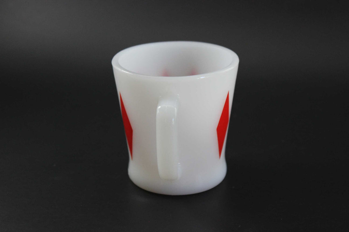 A second white glass coffee mug with a red harlequin diamond pattern, set against a dark gray background.