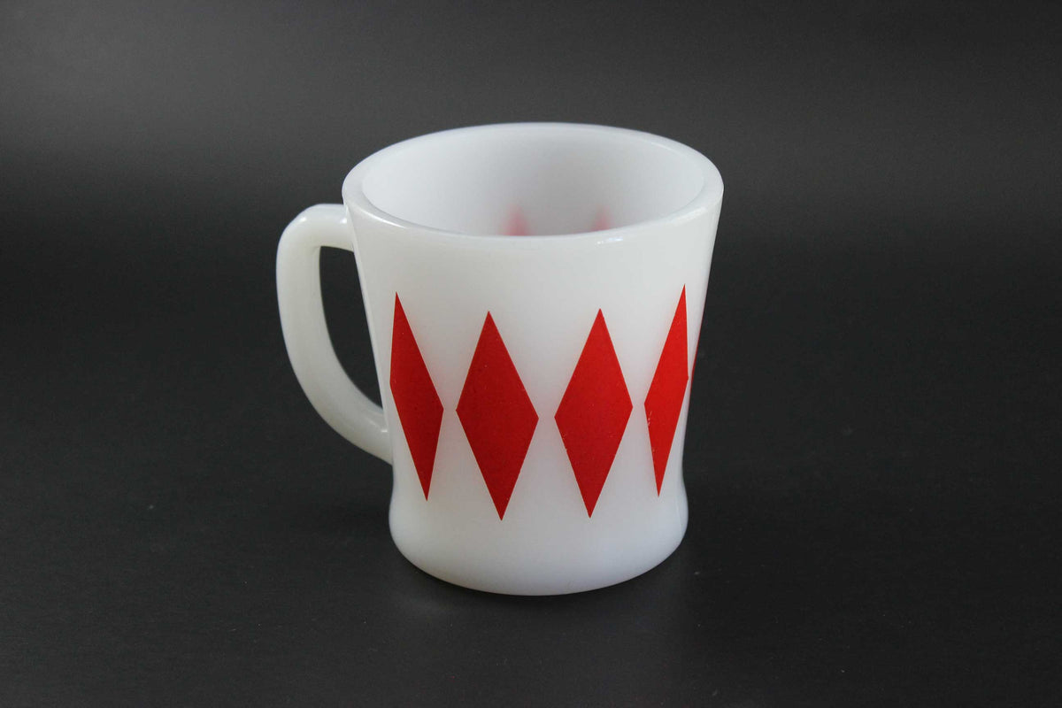 A second white glass coffee mug with a red harlequin diamond pattern, set against a dark gray background.
