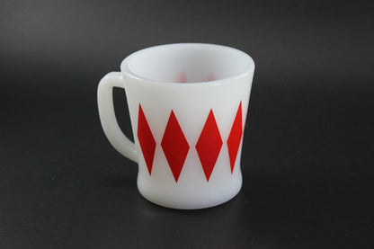 A second white glass coffee mug with a red harlequin diamond pattern, set against a dark gray background.