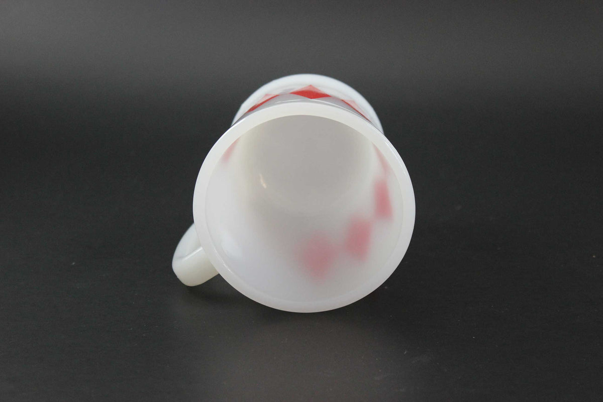A second white glass coffee mug with a red harlequin diamond pattern, set against a dark gray background.