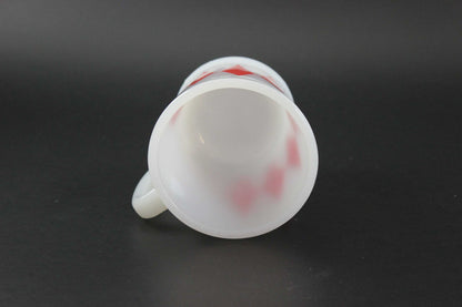 A second white glass coffee mug with a red harlequin diamond pattern, set against a dark gray background.