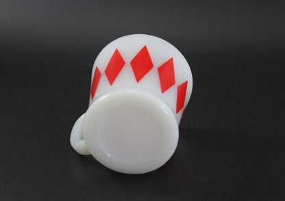 A second white glass coffee mug with a red harlequin diamond pattern, set against a dark gray background.