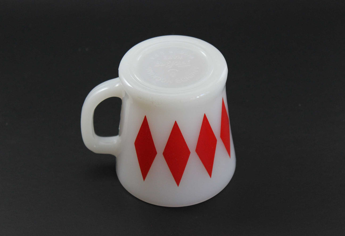 A second white glass coffee mug with a red harlequin diamond pattern, set against a dark gray background.