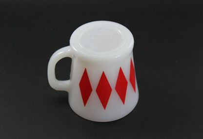 A second white glass coffee mug with a red harlequin diamond pattern, set against a dark gray background.