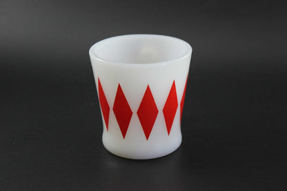 A white glass coffee mug with a red harlequin diamond pattern, set against a dark gray background.