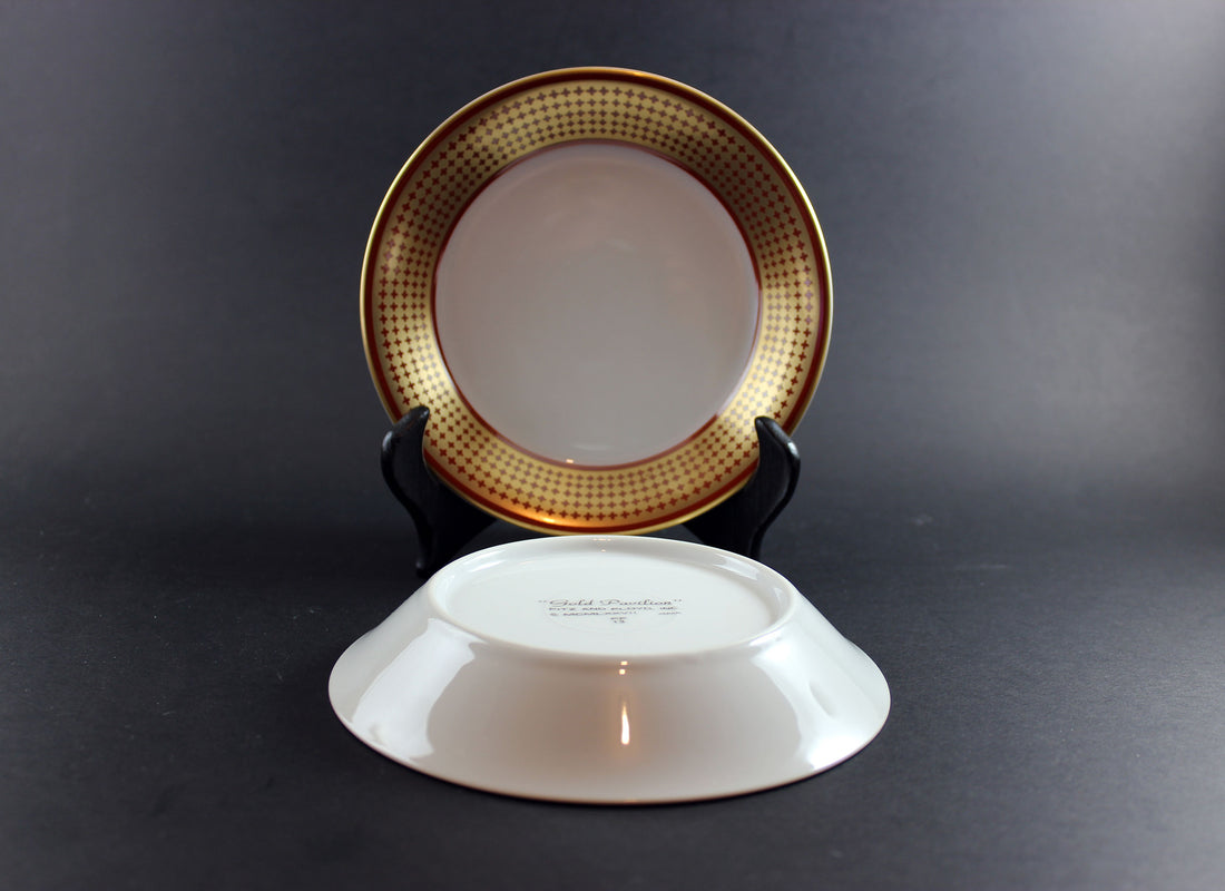 Two ceramic fruit bowls with decorative gold rims on a dark background