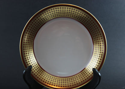 White bowl with gold decorative rim on a black stand against a dark background