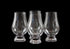 Four clear glass whisky glasses on a black background
