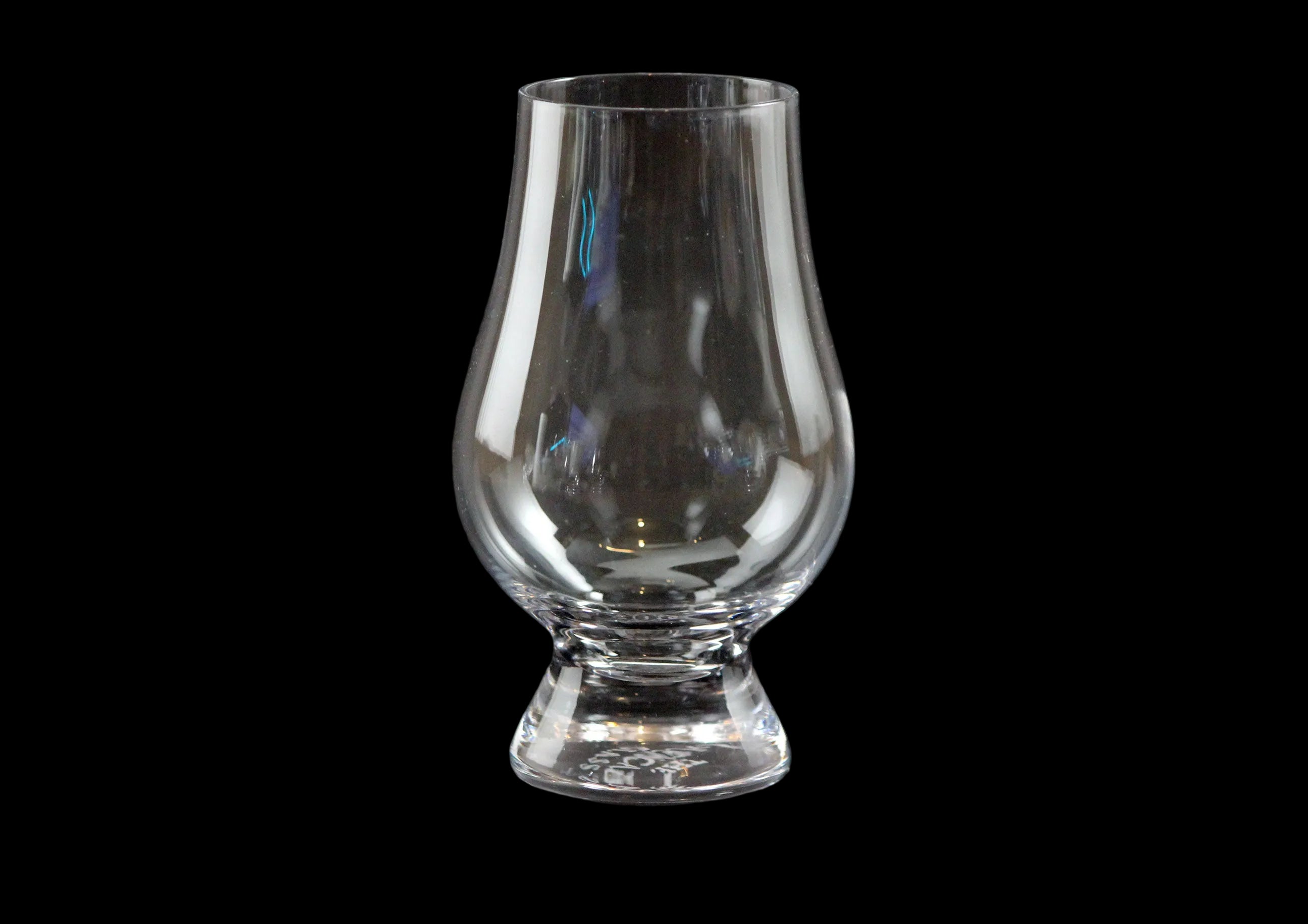 Clear glass whisky glass on a black background