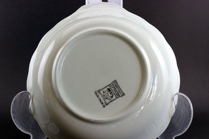 Light green ceramic dish with a visible brand logo on a black background