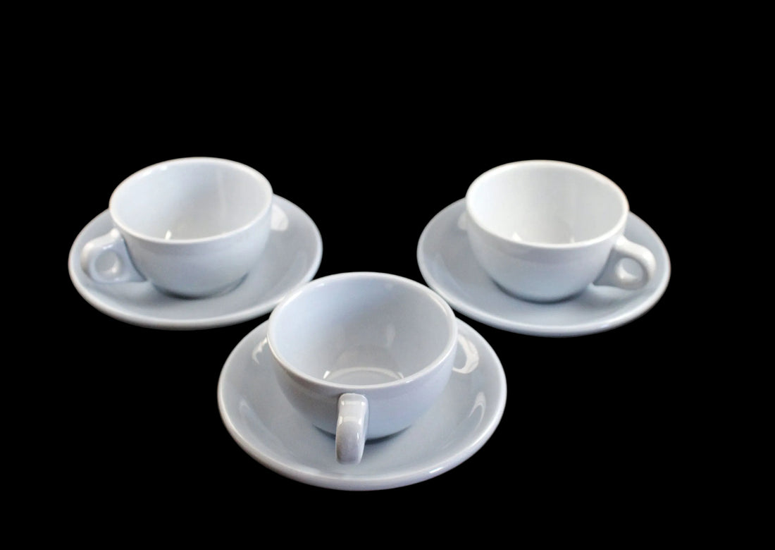 Three blue ceramic cups with saucers on a dark surface