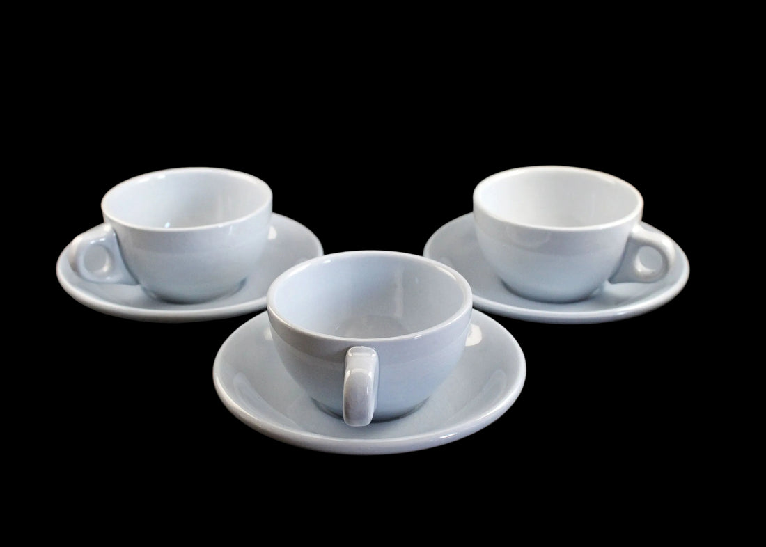 Three blue ceramic cups with saucers on a dark surface