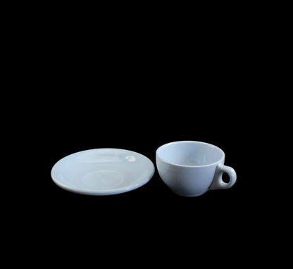 Light blue ceramic cup and saucer on a dark gray background