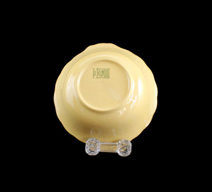 Yellow ceramic bowl on a clear stand against a black background