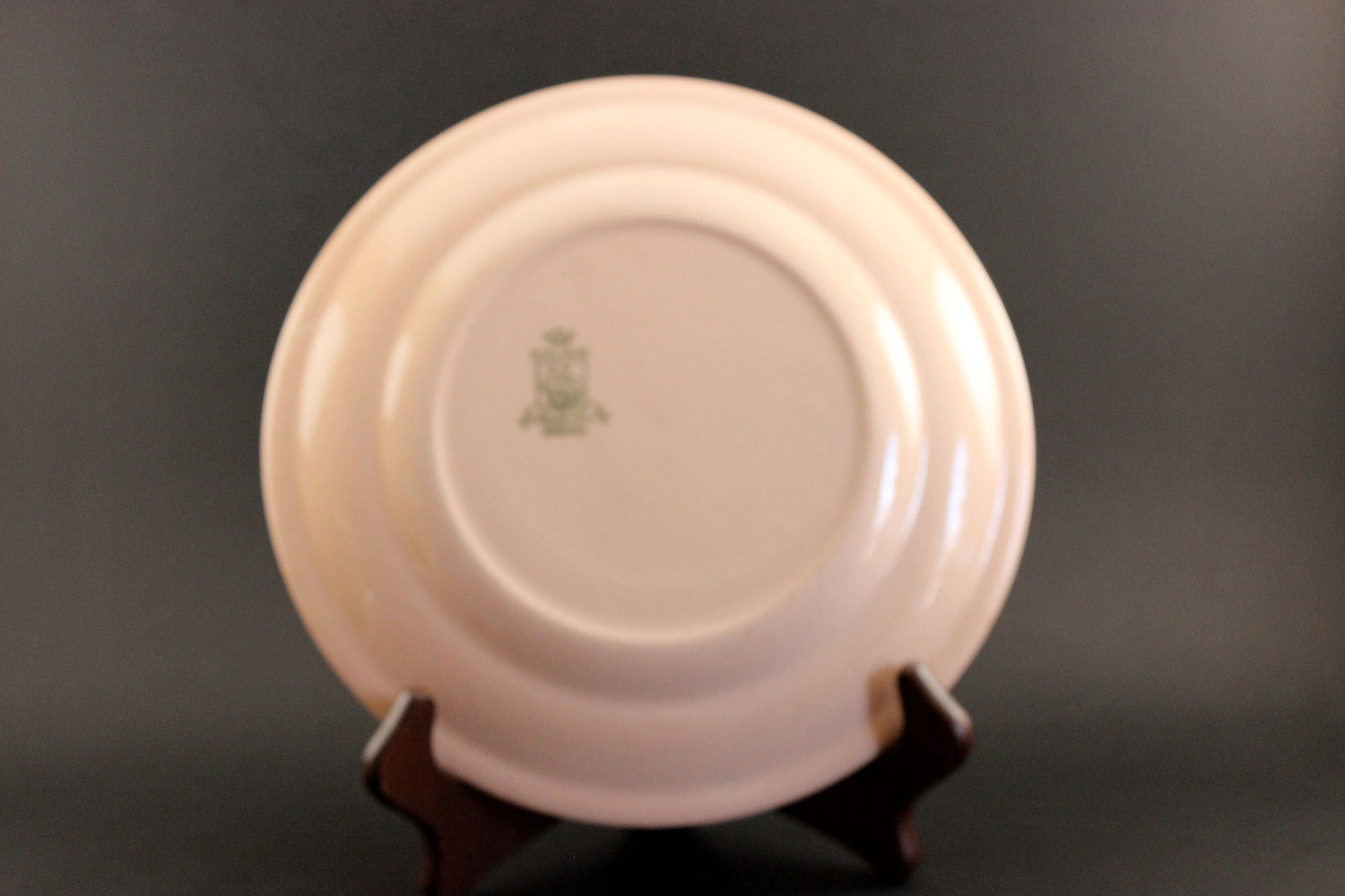 Pink ceramic plate with a logo on a dark background