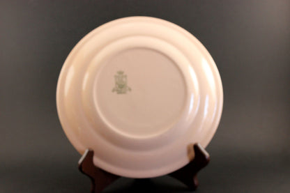 Pink ceramic plate with a logo on a dark background