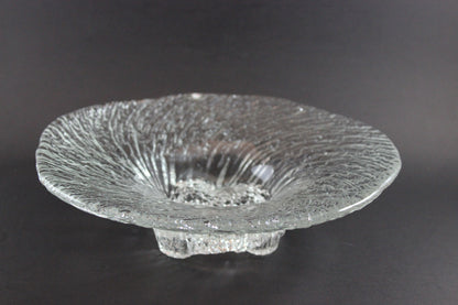 Clear glass footed bowl with textured surface on a dark background
