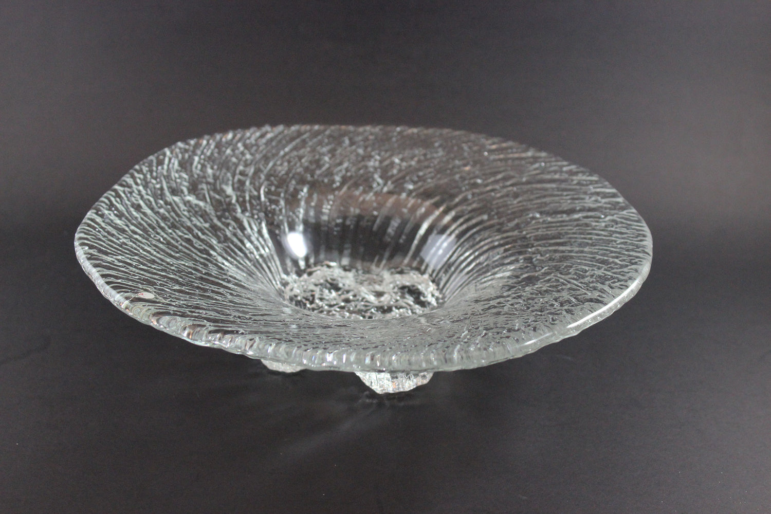 Clear glass bowl with textured surface on a dark background