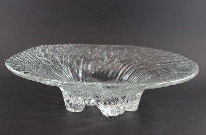 Clear glass footed bowl with textured surface on a dark background