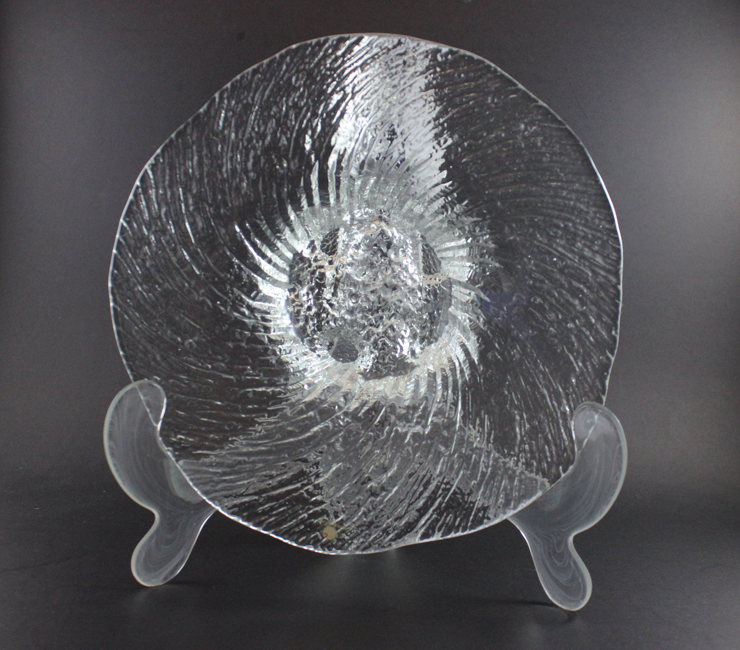 Clear glass footed bowl with textured surface on a dark background