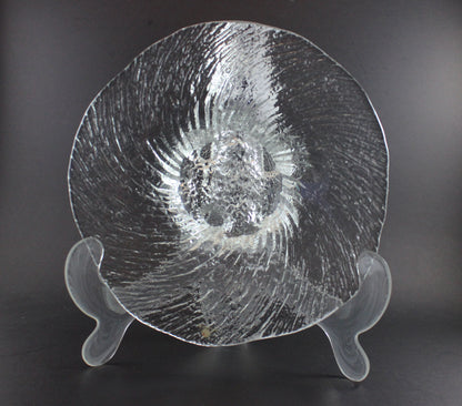 Clear glass footed bowl with textured surface on a dark background