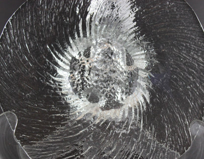 Clear glass footed bowl with textured surface on a dark background