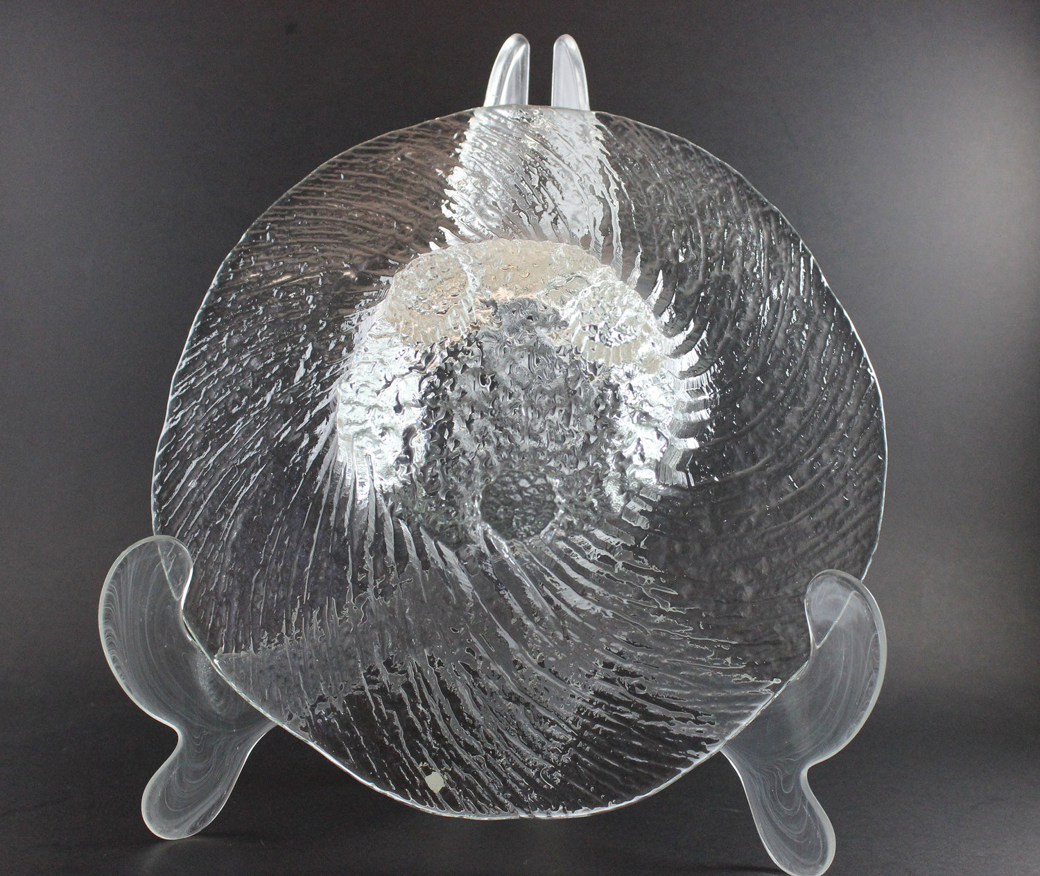 Clear glass footed bowl with textured surface on a dark background