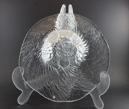 Clear glass footed bowl with textured surface on a dark background