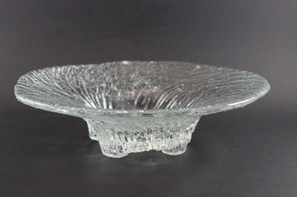Clear glass footed bowl with textured surface on a dark background