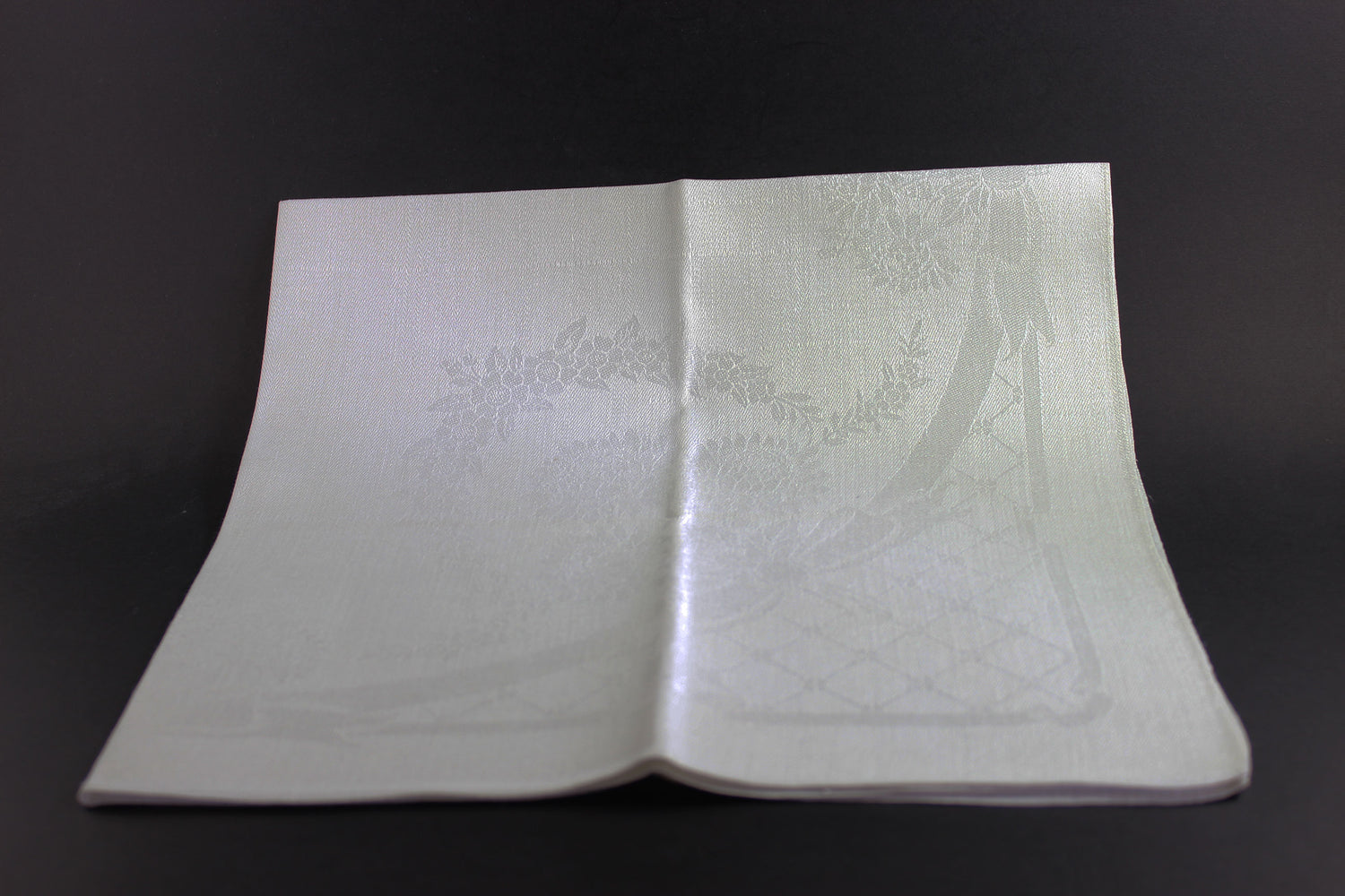 Folded white damask Irish linen napkin on black background.