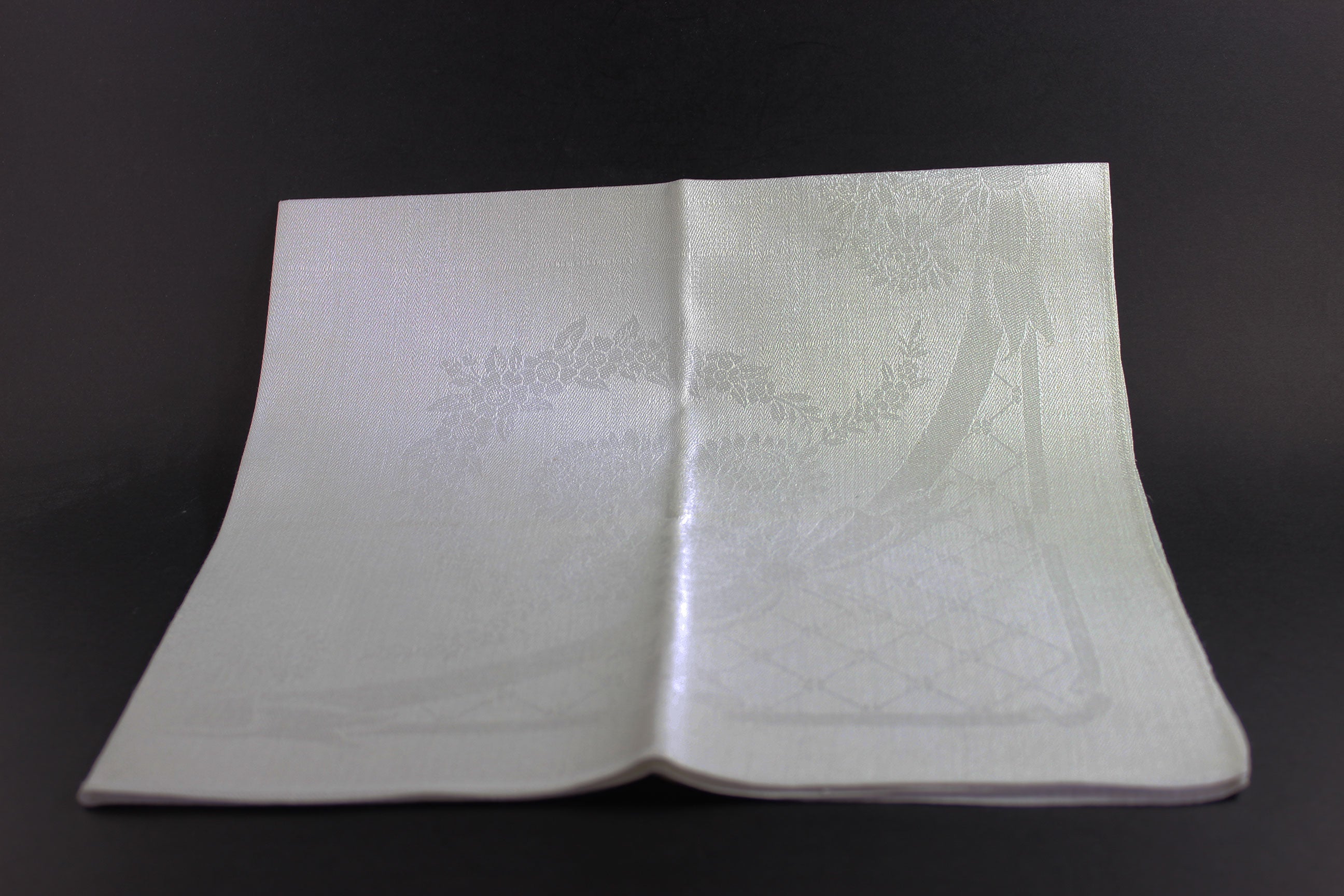 Folded white damask Irish linen napkin on black background.