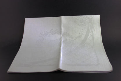 Folded white damask Irish linen napkin on black background.