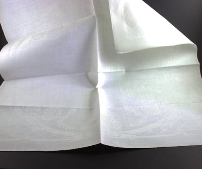 Unfolded white damask Irish linen napkin on black background.
