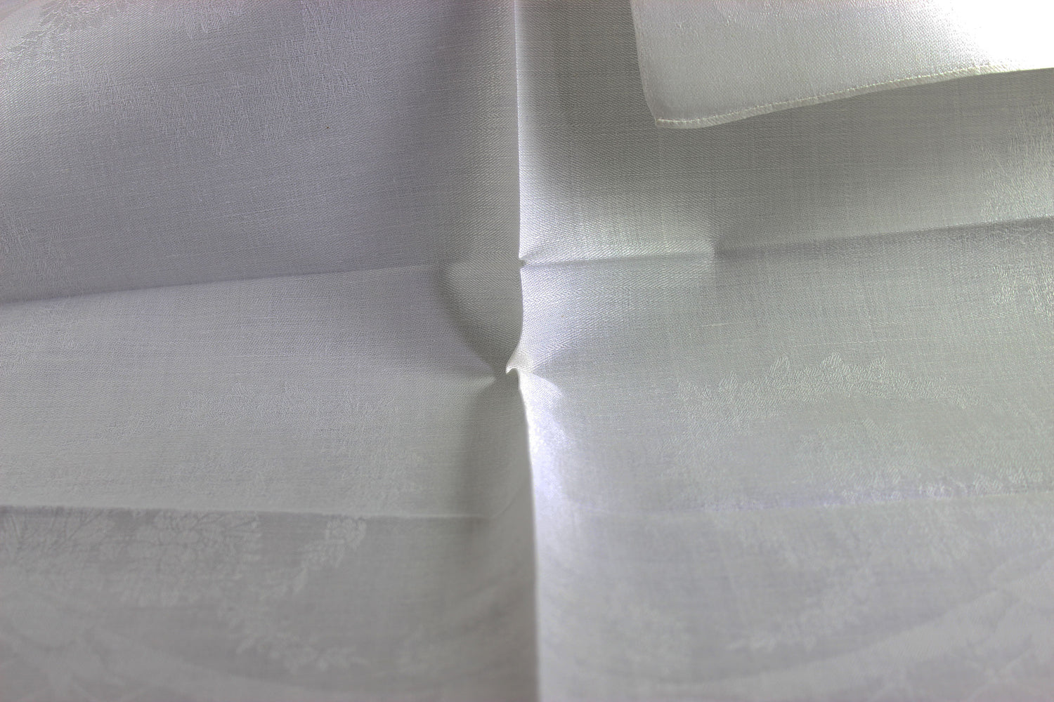 Close-up of white damask linen napkin with a subtle pattern