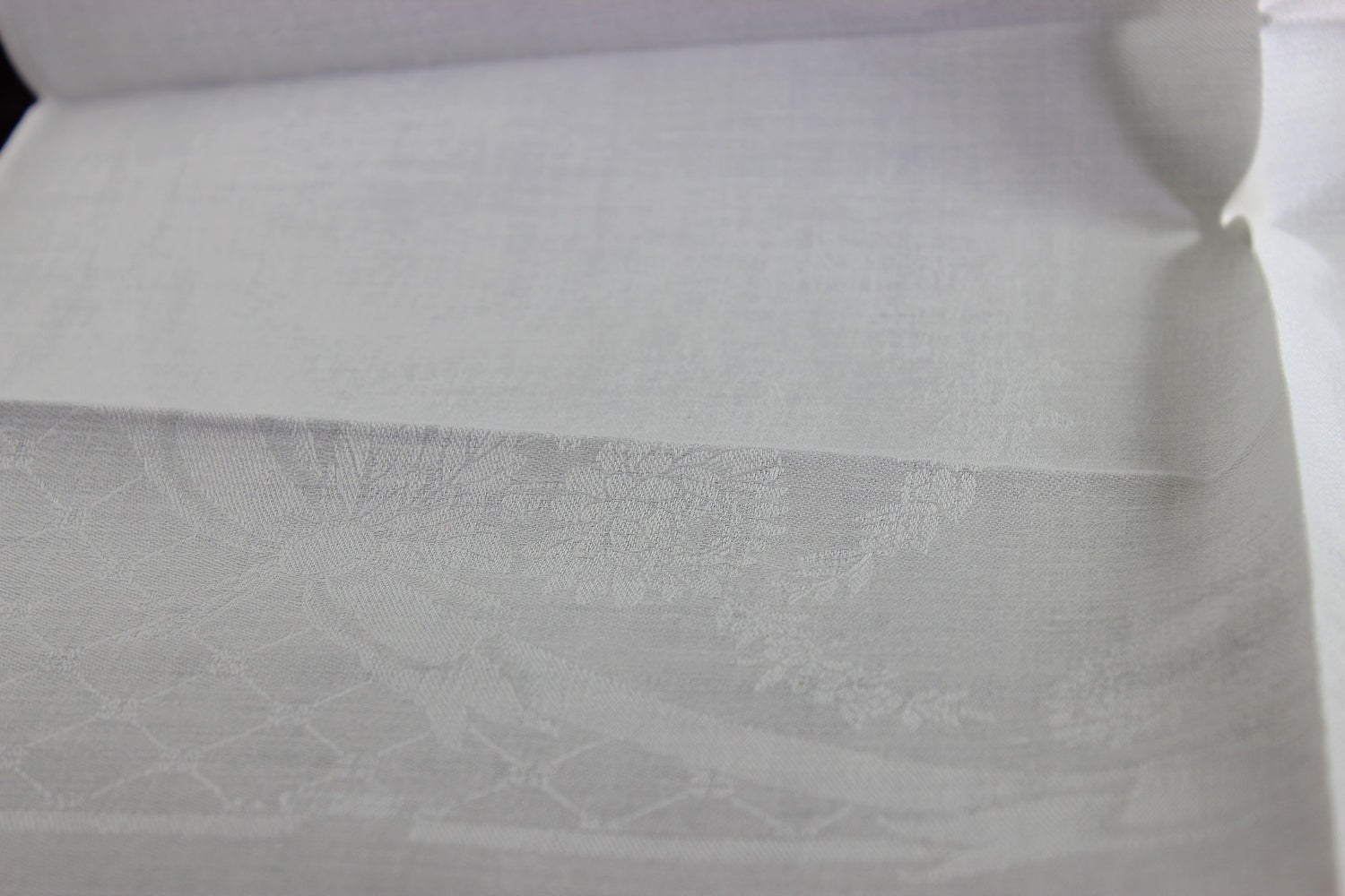 Close-up of white damask linen napkin with a subtle pattern