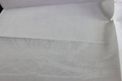 Close-up of white damask linen napkin with a subtle pattern