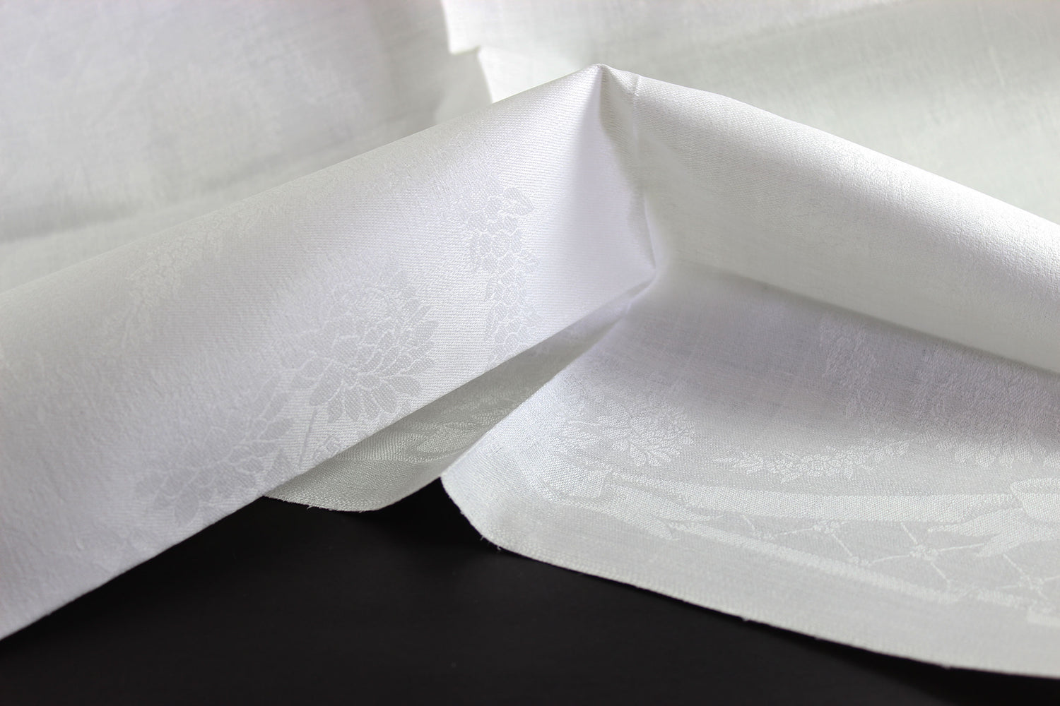 Close-up of white damask linen napkin with a subtle pattern