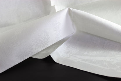Close-up of white damask linen napkin with a subtle pattern