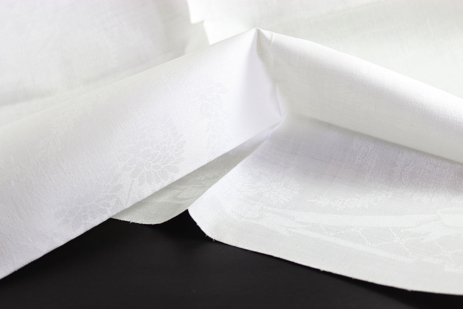 Close-up of white damask linen napkin with a subtle pattern
