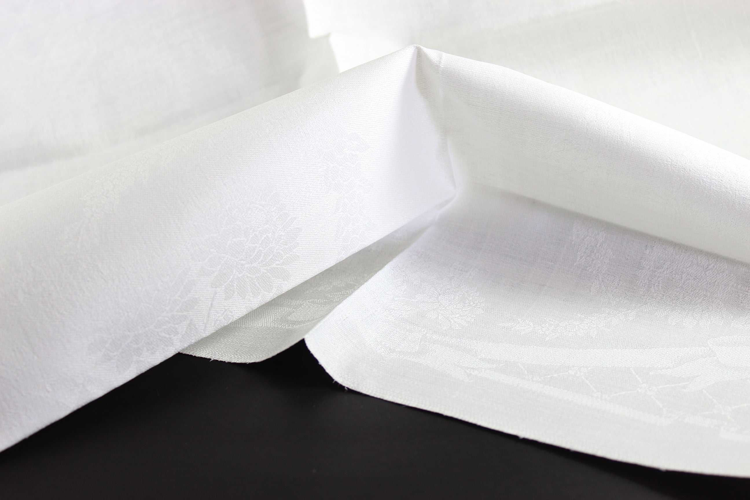 Close-up of white damask linen napkin with a subtle pattern