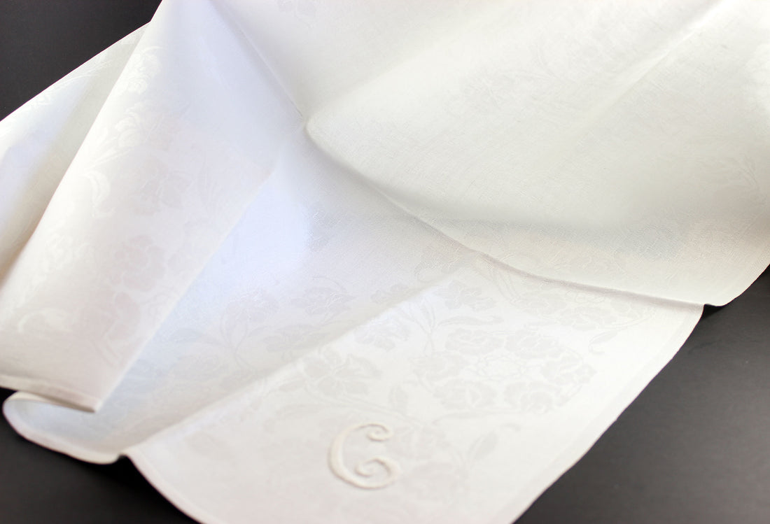 Irish Linen napkins with embroidered monogram. Roses and Daffodil design. Black background.