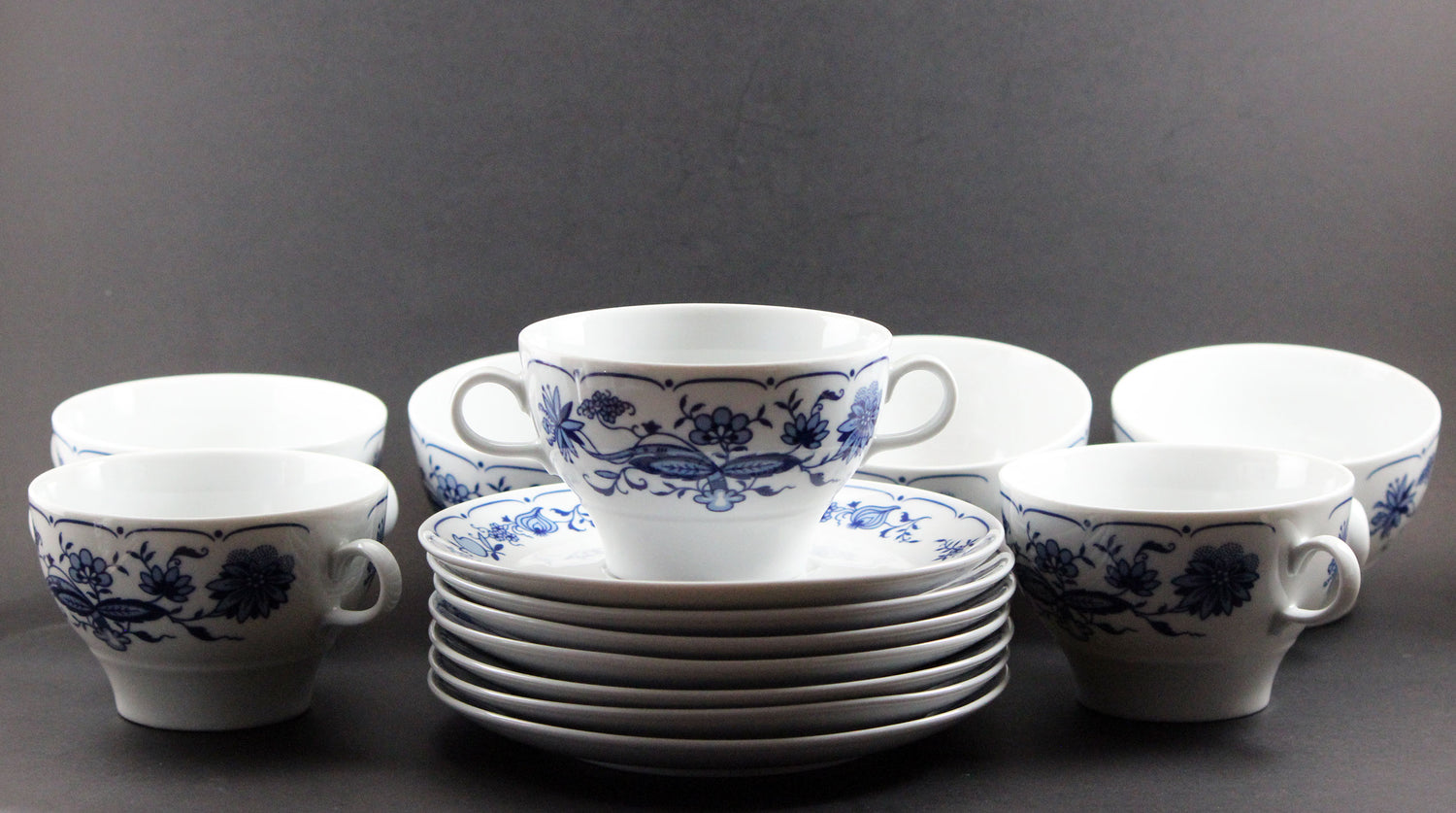 Set of white porcelain soup bowls with blue floral patterns on a gray background