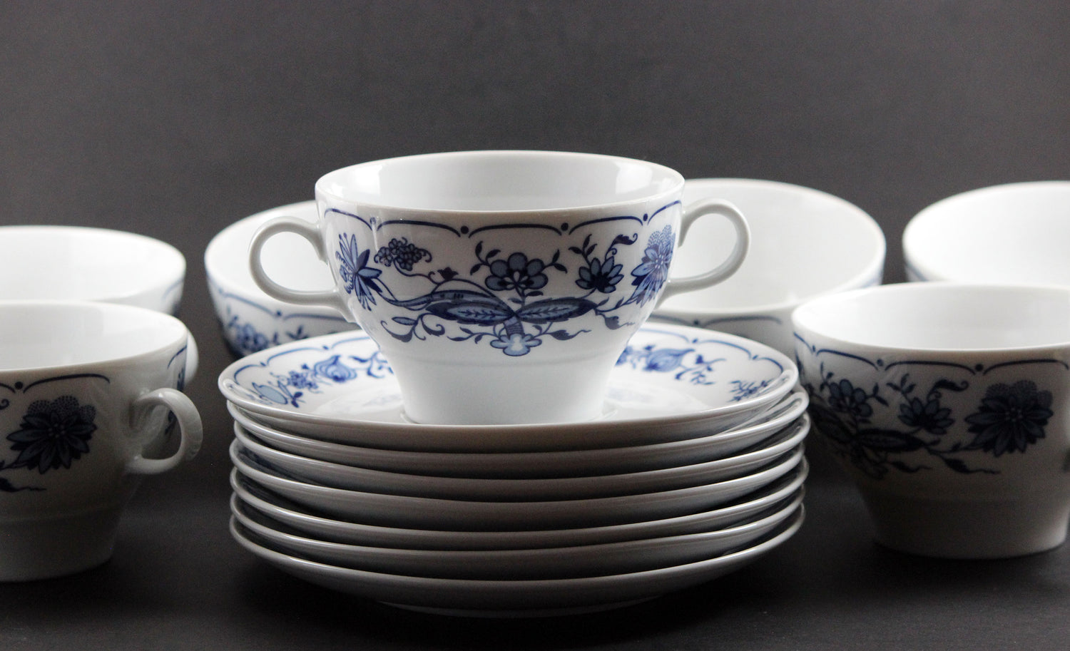Set of white porcelain soup bowls with blue floral patterns on a gray background